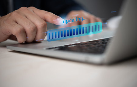 Close up of a hand interacting with a laptop showing a digital progress bar for updating software,...
