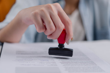 Businesswoman authorizing a contract with a notary rubber stamp, symbolizing certification and compliance.concept business law, finance, and administration.の写真素材