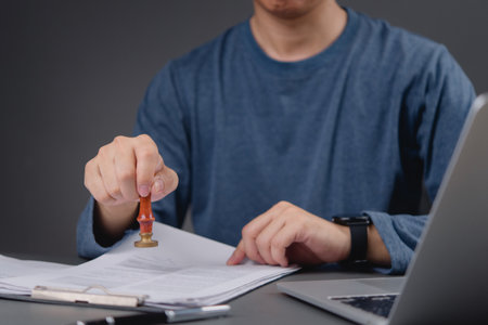 professional office worker using a stamp on paperwork, demonstrating the administrative process and the formal approval of documents.の写真素材
