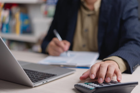 Man working on financial paperwork and using calculator, representing corporate accounting and...