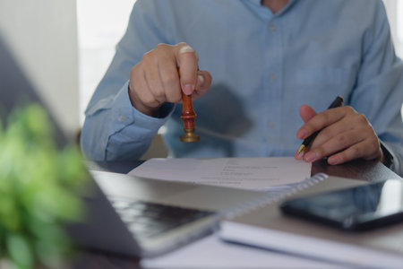 Close-up of hand stamping document with pen in hand. Concept of contract agreement, paperwork...