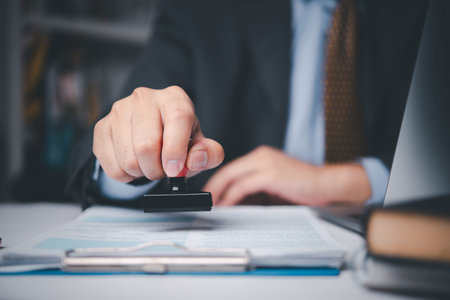 Businessman stamping contract document on desk, symbolizing legal approval, corporate agreement, and...