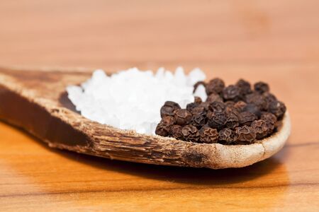 Coarse salt and pepper corns on wooden spoon tableの写真素材