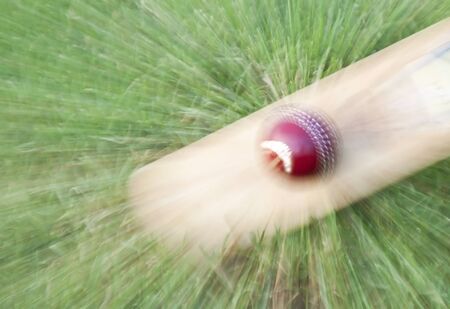 Cricket ball on bat zoom warped on green grassの写真素材