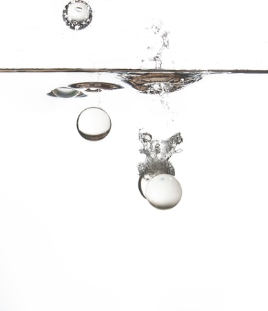 Clear glass balls falling into water creating a splashの写真素材