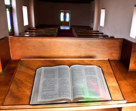Empty church with lead glass doors with Bible lying open for a sermonのeditorial素材