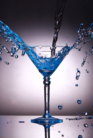 Martini glass with water splash with a blue color tintの写真素材