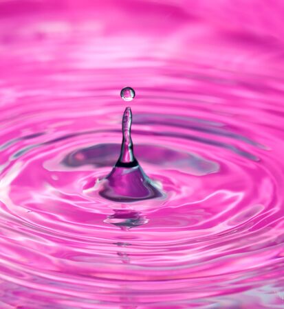 Water drop in a pink surface making concentric circlesの写真素材