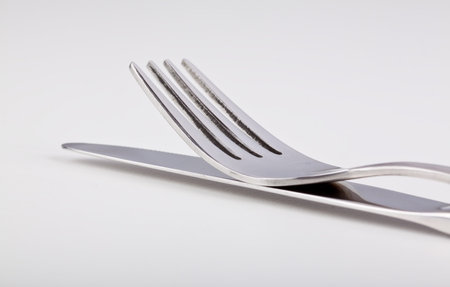 Fork lying on top of the knife on a silver surface