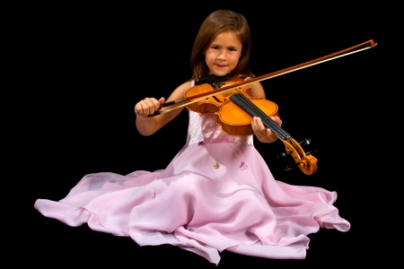 Girl playing violin in pink dress concentration on blackの写真素材