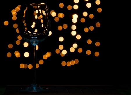 Wine glass on wooden table with dark and bokeh background distant lightsの写真素材