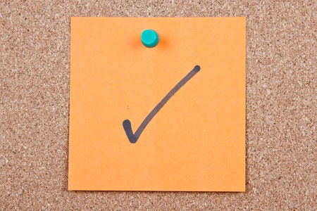 Post it note on wood in orange with correct markの写真素材