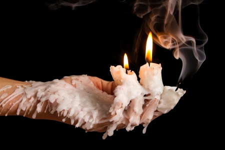 Three candle sticks on fingers buring with wax flowの写真素材