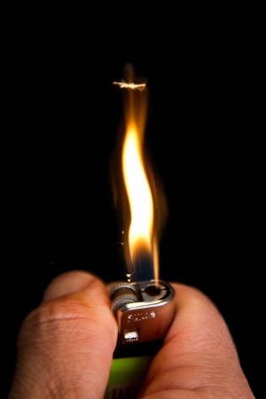 Hand with lighter igniting sparks close-up on dark backgroundの写真素材