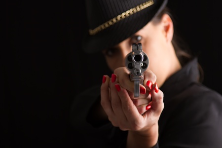 Dangerous woman in black with silver handgun and stylish hatの写真素材