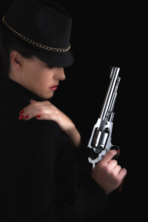 Dangerous woman in black with silver handgun and stylish hat artistic conversionの写真素材