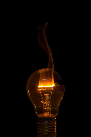 Broken light bulb burn out with flame on filament with smoke
