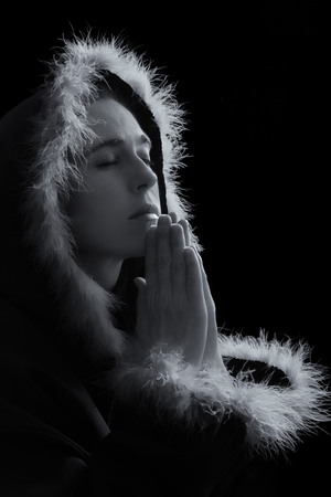 Portrait of sad woman in black cape praying feathered rim artistic conversionの写真素材