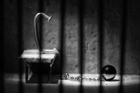 Conceptual jail photo with iron nail ball and chain behind out of focus bars artistic conversionの写真素材