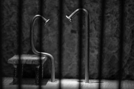 Conceptual jail photo with iron nail sitting behind out of focus bars artistic conversionの写真素材