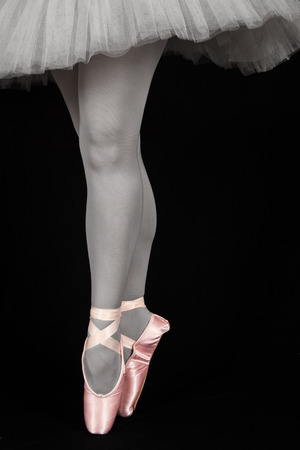 Ballet dancer standing on toes while dancing on black background artistic converionの写真素材