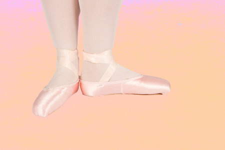 Ballet dancer standing on peach floor while dancing in pink tutu artistic converion