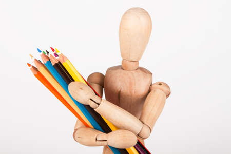 Small wood mannequin standing with bunch of colour pencil isolated on white backgroundの写真素材