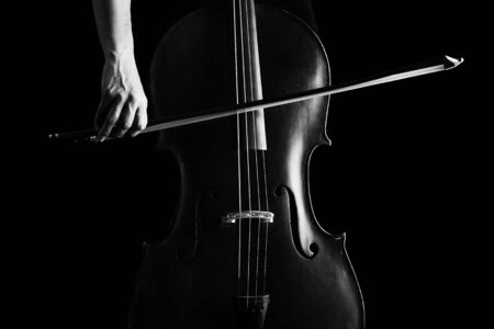 Beautiful brunette playing a cello with selective light in black dress artistic conversionの写真素材
