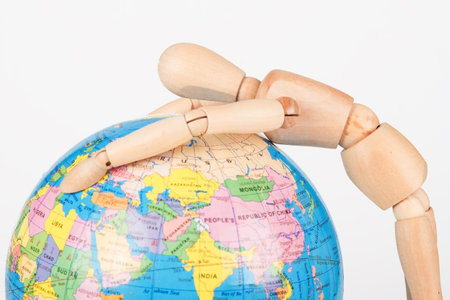 Brown wood mannequin holding concerned a globe to protect
