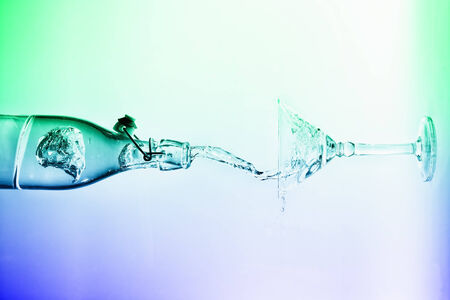 Clear water pour horizontal out of bottle splash into glass with a white back lightingの写真素材