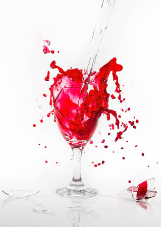 Red water spill from a broken wine glass on a white backgroundの写真素材