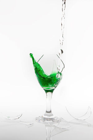 Green water spill from a broken wine glass on a white backgroundの写真素材