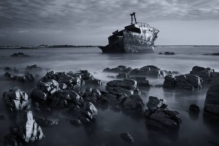 Old shipwreck long exposure on the rocks at sunset artistic conversionの写真素材