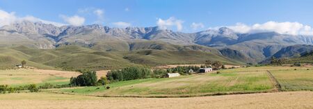 Panoramic farm landscape with high mountains and green fieldsの写真素材