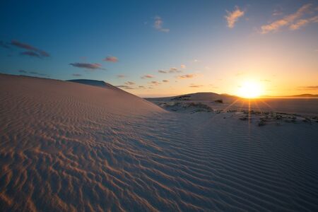 Glorious sunset over a rippled sand dune next to a lagoonの写真素材