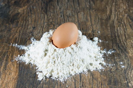 Whole egg lay on heap of flour ready to be mixed for breadの写真素材