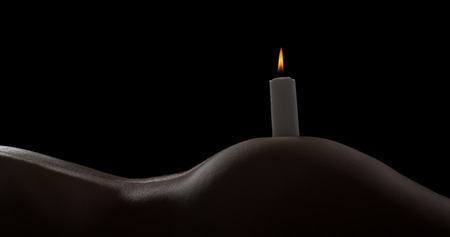 Body scape of a well-shaped woman with a burning candle on her bumの写真素材