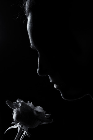 Silhouette of a woman face smelling rose in black and white rim lightingの写真素材
