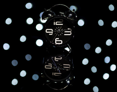 Bokeh spots of lights with alarm clock on a reflective surface