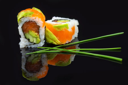 Sushi arranged on a shiny black surface looking very delicious