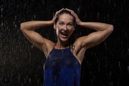 Beautiful woman in blue dress stands in rain at night getting wetの写真素材
