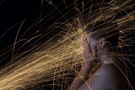 Long exposure photo of a woman blocking glowing sparks artistic conversionの写真素材