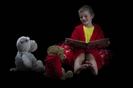 Funny boy with many stuffed animals reading a book before bed time artistic conversionの写真素材