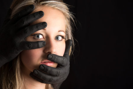 Frightened blonde woman grabbed by black hands on her face