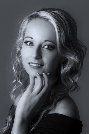 Beautiful blond woman in curly hair and black top on a grey background artistic conversionの写真素材