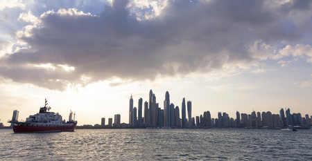 Landscape of the Dubai city skyline at sunset with clouds and shipのeditorial素材