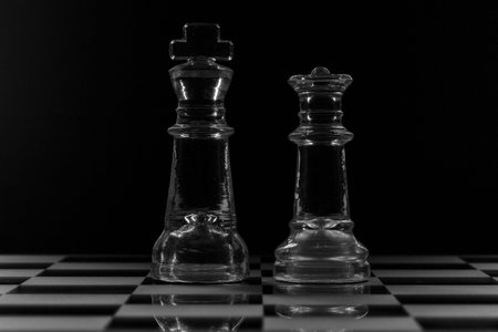 King and queen glass chess pieces facing each other in black and white
