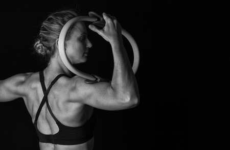 Fit woman with shaped muscles on her back and training hoop in artistic conversionの写真素材