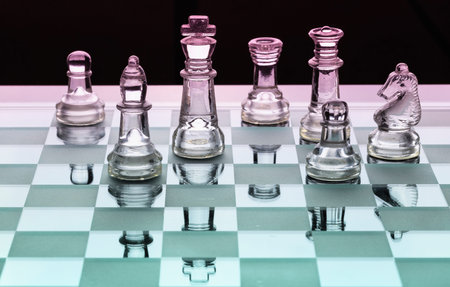 Assortment of glass chess pieces on a board with pink and green shade