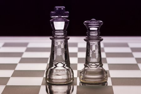 King and queen glass chess pieces facing each other in black and whiteの写真素材